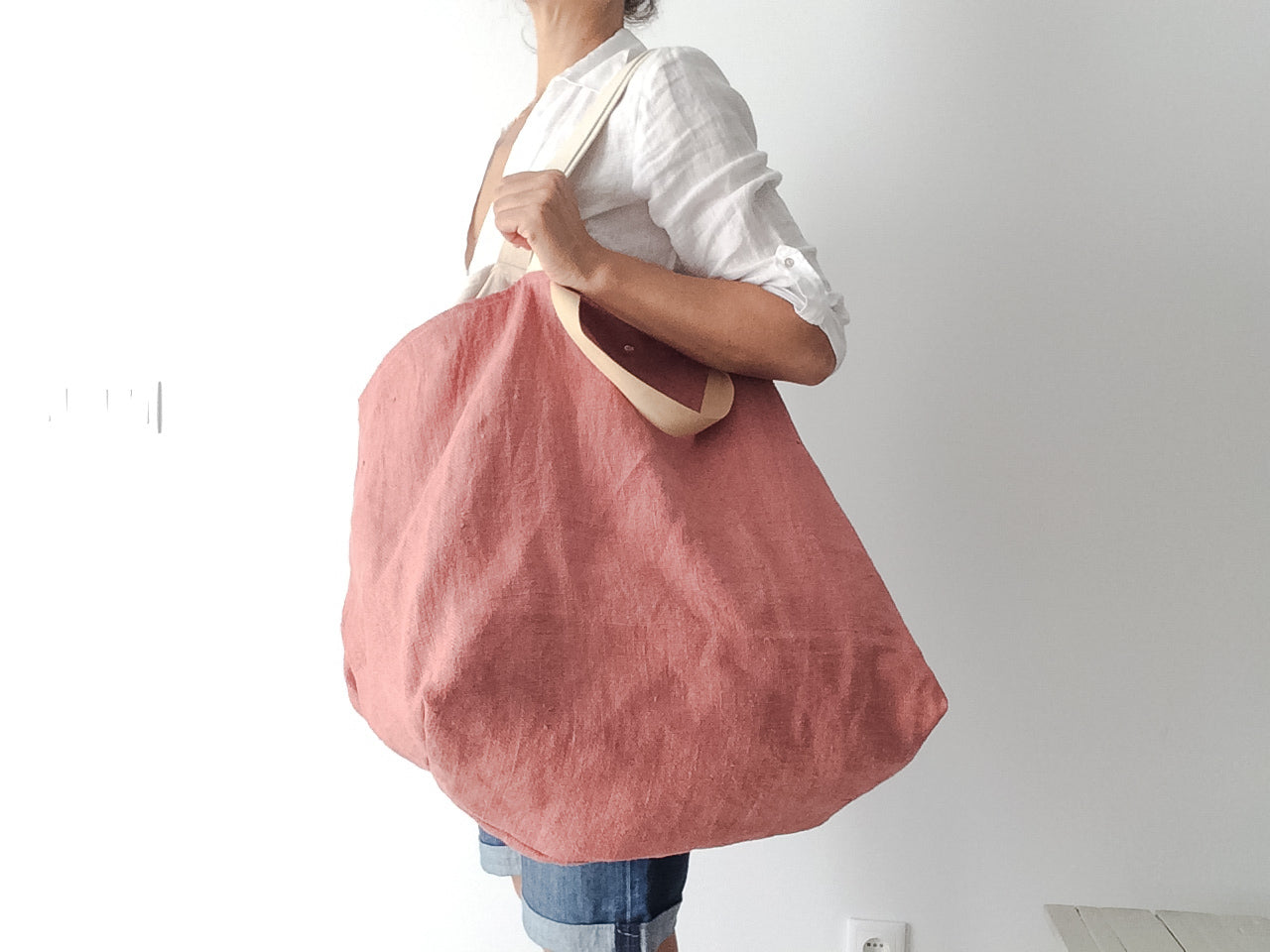 woman wearing a white linen shirt and a big beach linen bag in natural color