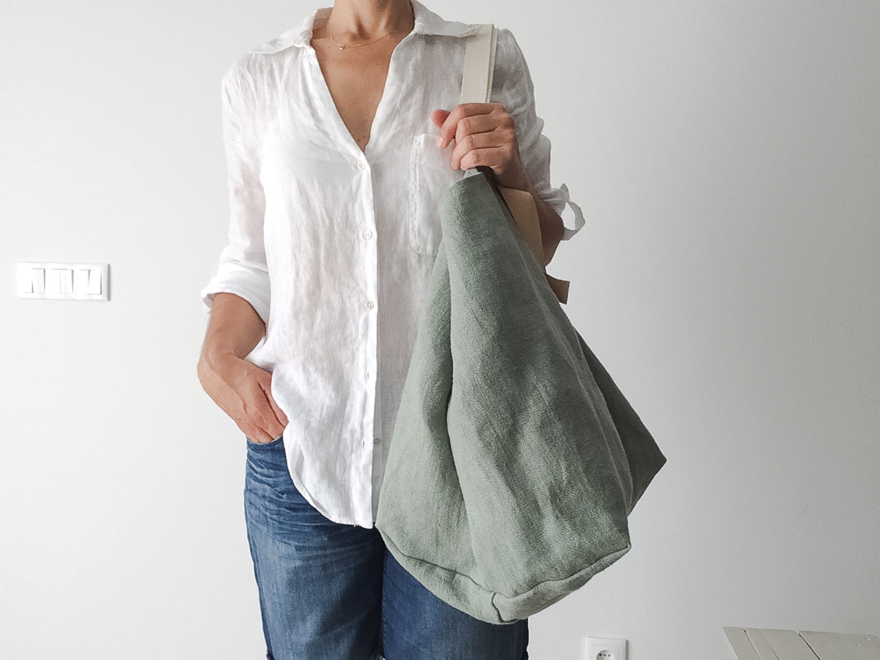 women wearing a white linen shirt wears a big beach bag in green linen 